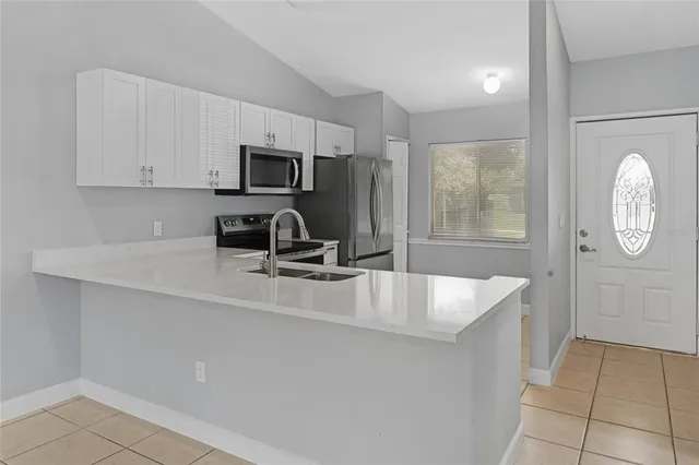a kitchen with kitchen island a counter top a sink a stove and a window