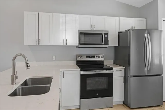 a kitchen with refrigerator a microwave a sink and cabinets