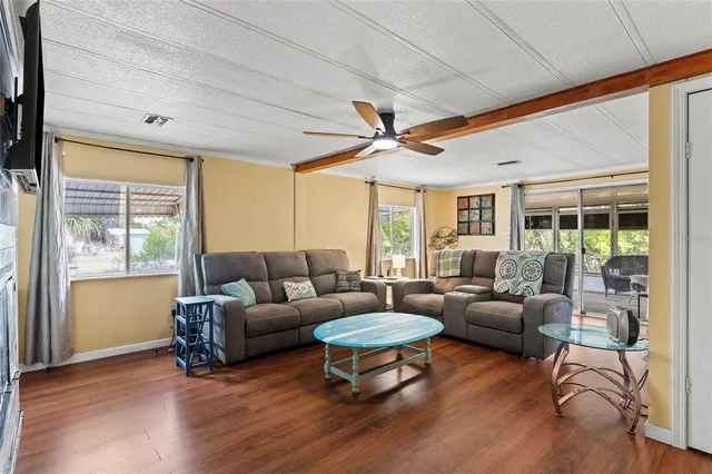 a living room with furniture a ceiling fan and a large window
