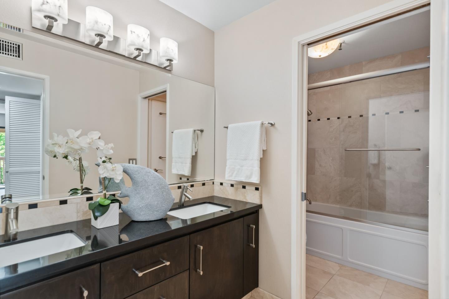 49 Showers Drive, Unit E250 Mountain View, CA 94040 - Photo 16 of 27 a bathroom with a granite countertop sink a mirror and a shower