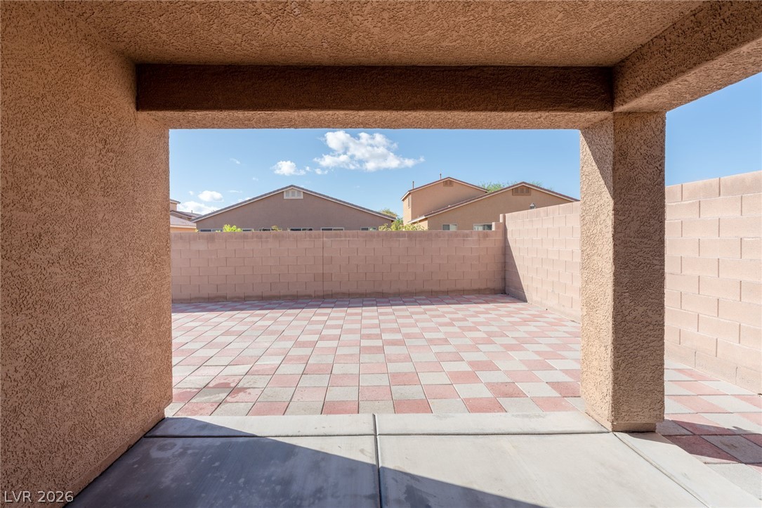 8079 Buffalo Ranch Avenue Las Vegas, NV 89147 - Photo 25 of 29 A covered back patio looks out over a private, paved courtyard surrounded by block fencing.
