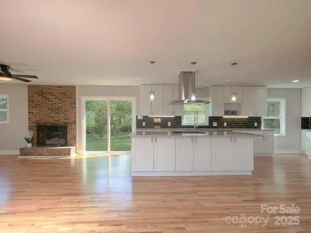 a kitchen with stainless steel appliances granite countertop a refrigerator a stove a sink dishwasher and white cabinets with wooden floor