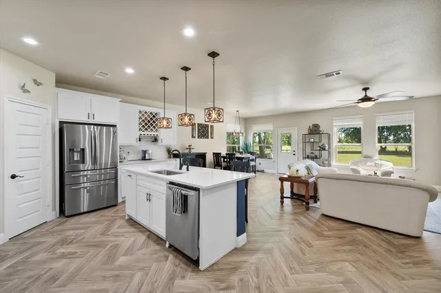 a kitchen that has a lot of white cabinets and stainless steel appliances