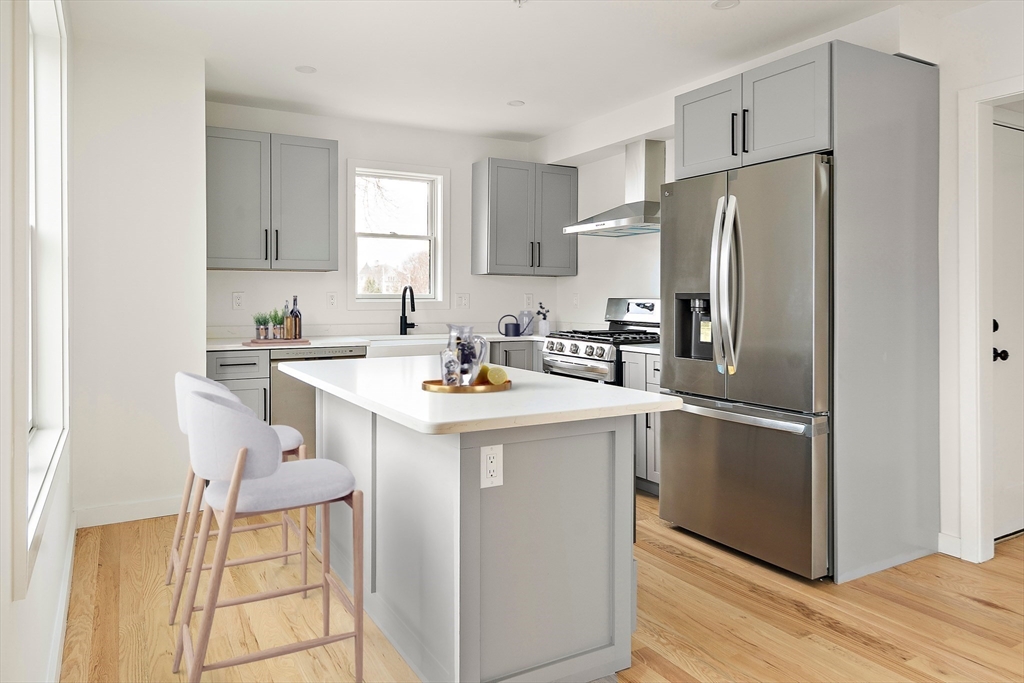 25 Hillsboro Street, Unit 1 Boston, MA 02125 - Photo 1 of 14 a kitchen with stainless steel appliances a refrigerator a sink a stove and white cabinets with wooden floor
