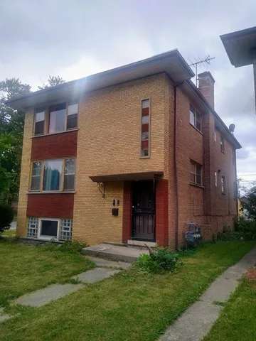 a brick house with a yard and a large tree