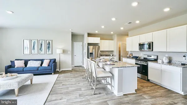 a living room with furniture a rug kitchen view and a large window