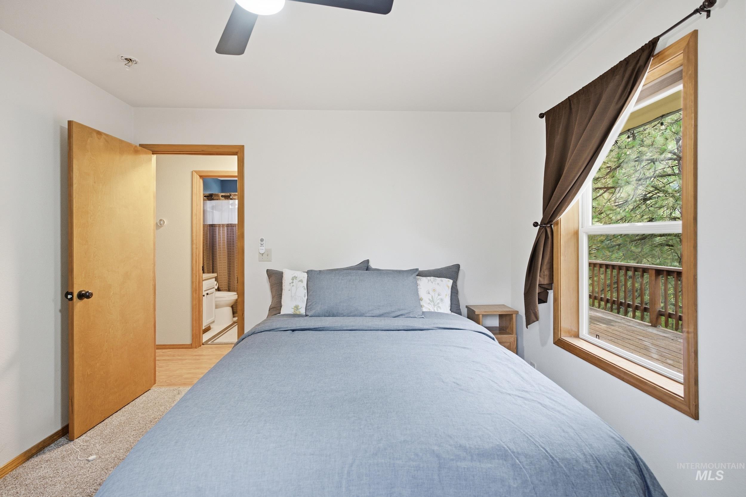 3980 North Pine-Featherville Road Mountain Home, ID 83647 - Photo 17 of 35 Bright room featuring a ceiling fan with integrated lighting, a wooden window frame, and a partial outdoor deck visible