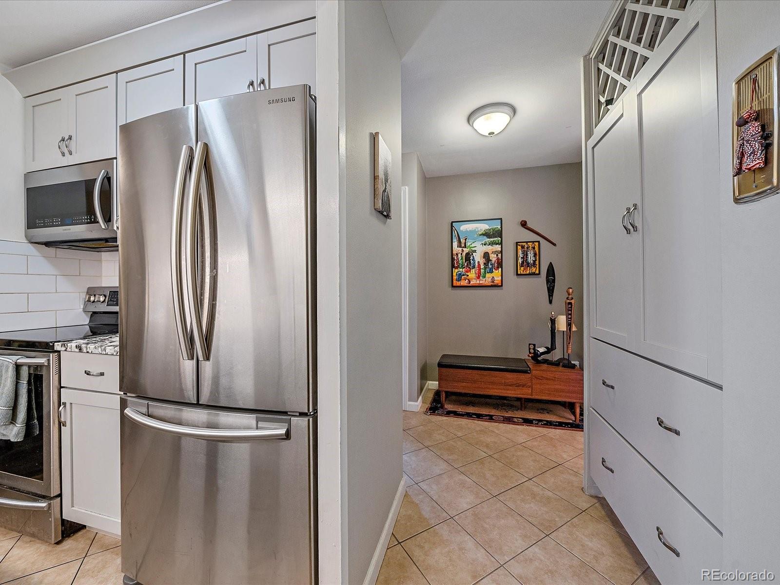 1111 Ash Street, Unit 307 Denver, CO 80220 - Photo 4 of 21 a kitchen with stainless steel appliances a refrigerator and cabinets