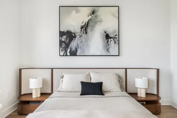 a bedroom with a bed and painting on the wall