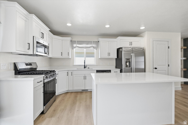 730 West 500 North Smithfield, UT 84335 - Photo 12 of 46 Bright kitchen featuring white cabinetry, light-toned wood-finish flooring, and a central island with a solid surface countertop