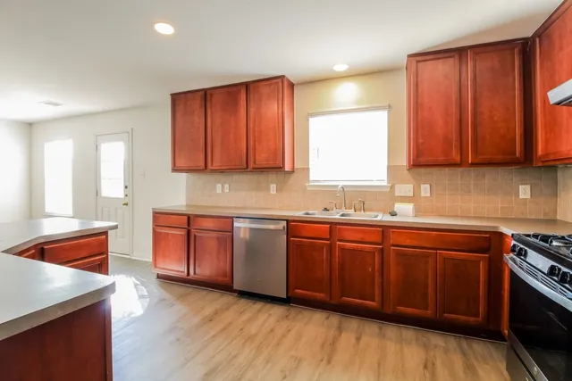 a kitchen with stainless steel appliances granite countertop wooden cabinets a sink and dishwasher with wooden floor