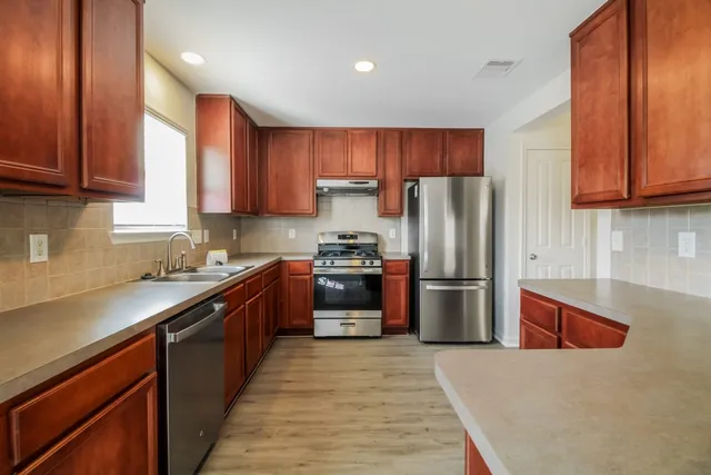 a kitchen with stainless steel appliances granite countertop a refrigerator stove a sink and dishwasher