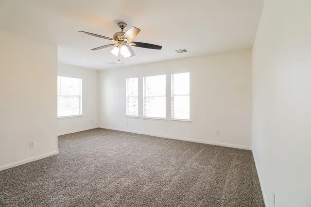 an empty room with windows and fan