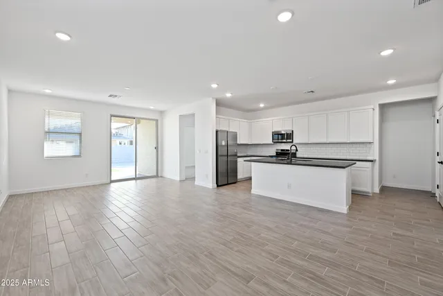 a view of kitchen with kitchen island wooden floors appliances and cabinets