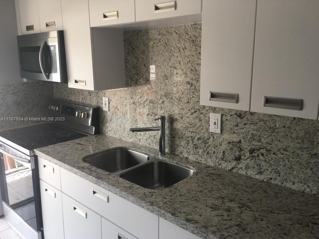 1852 Southwest 7th Street, Unit 309 Miami, FL 33135 - Photo 4 of 12 a kitchen with granite countertop a sink and cabinets