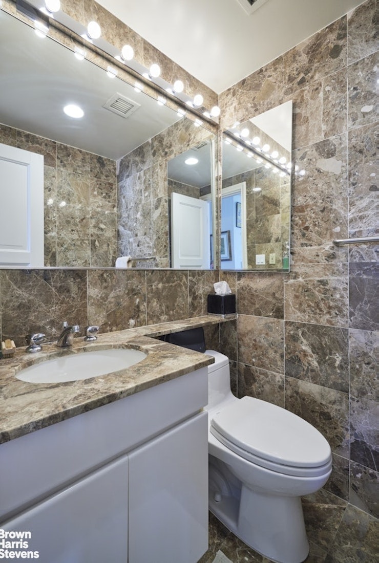 157 East 74th Street, Unit 10B Manhattan, NY 10021 - Photo 10 of 14 a bathroom with a granite countertop toilet sink and mirror