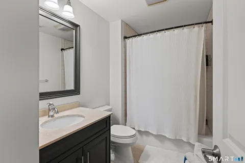 a bathroom with a granite countertop sink toilet and shower