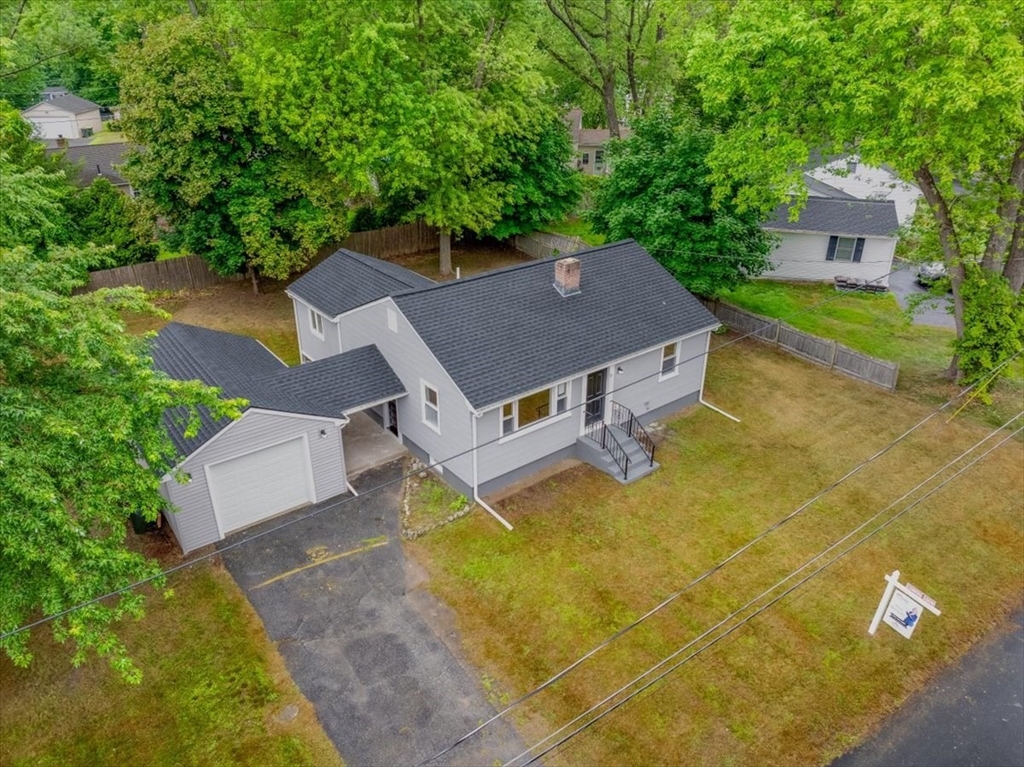 an aerial view of a house with swimming pool and large trees