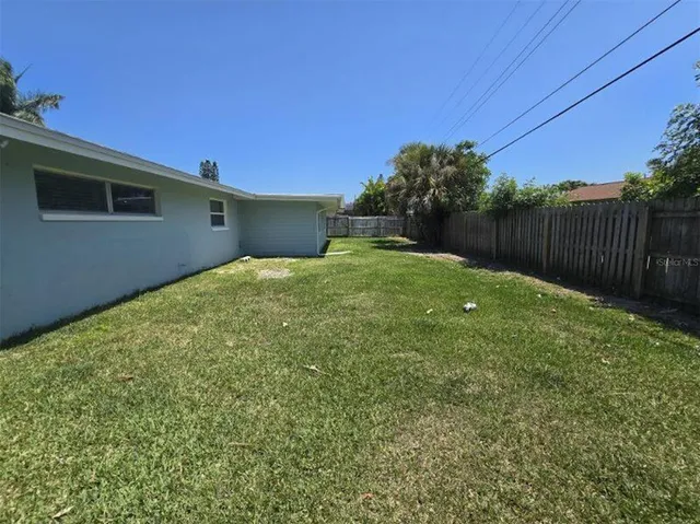 a backyard of a house with plants and wooden fence
