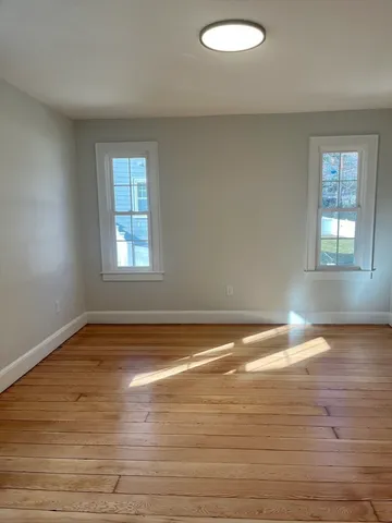 a view of empty room with window and wooden floor
