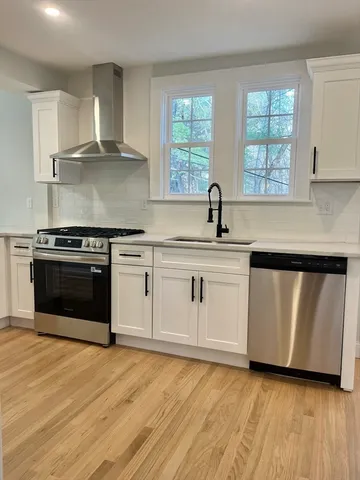a kitchen with white cabinets appliances a sink and a window