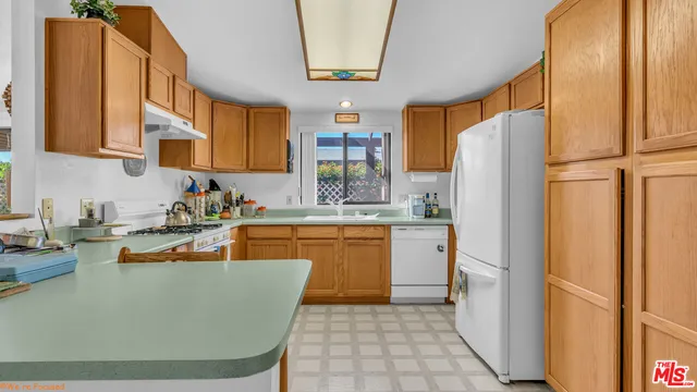 a kitchen with stainless steel appliances granite countertop a refrigerator a sink a stove a washer dryer and a dining table