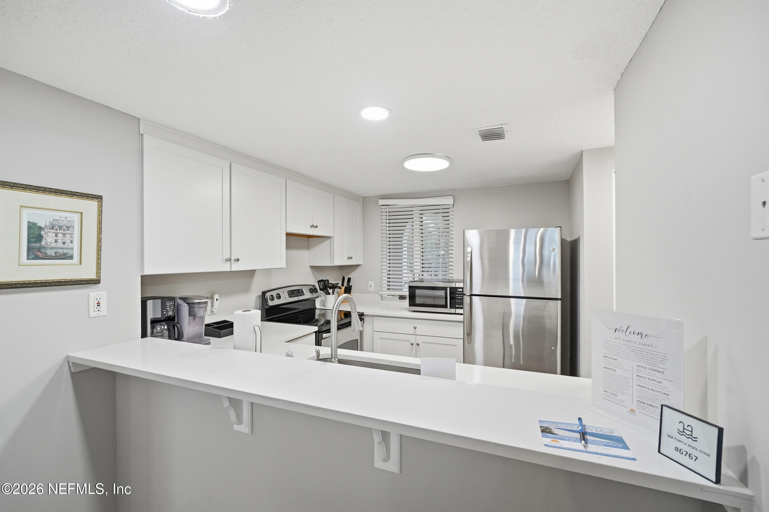 1817 Turtle Dunes Place Fernandina Beach, FL 32034 - Photo 14 of 34 a kitchen with white cabinets and stainless steel appliances