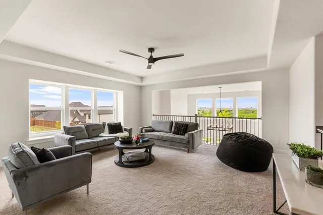 a living room with furniture ceiling fan and a large window