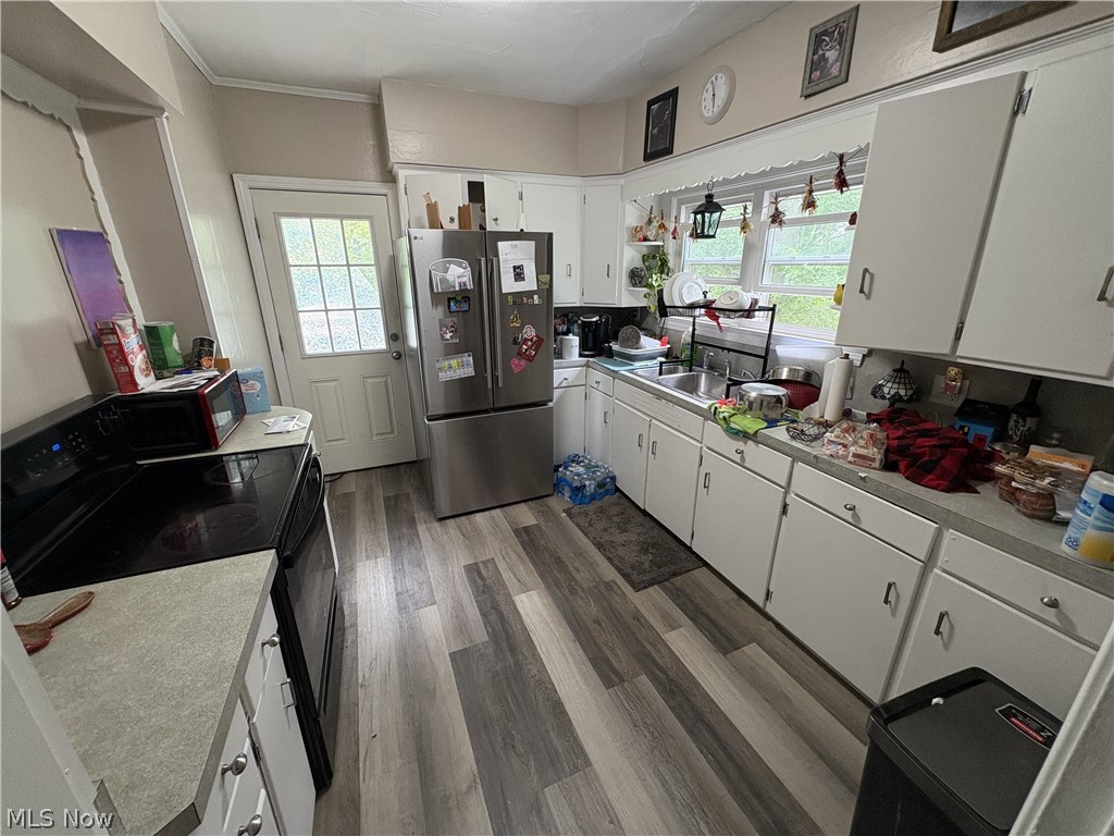 727 Wooster Road North Barberton, OH 44203 - Photo 9 of 37 727 (4-Bed) - Kitchen space featuring wood-finish flooring, white cabinetry, a light-toned countertop, a window above the sink, and a glass-paned exterior door