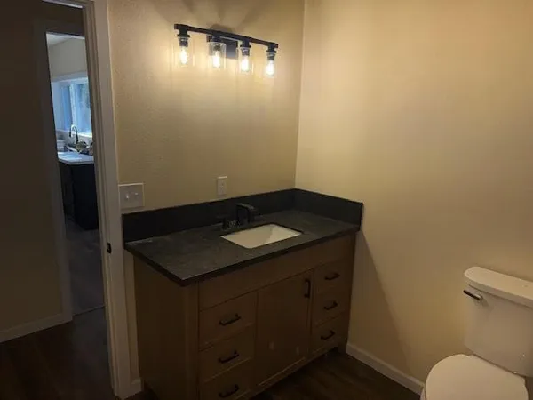 a bathroom with a granite countertop sink and a toilet