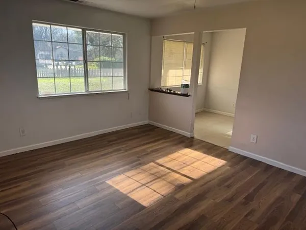 an empty room with wooden floor and windows