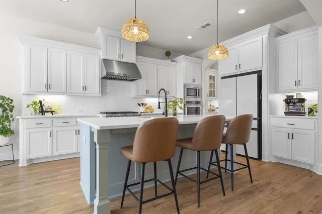 a kitchen with stainless steel appliances a dining table chairs stove refrigerator and cabinets