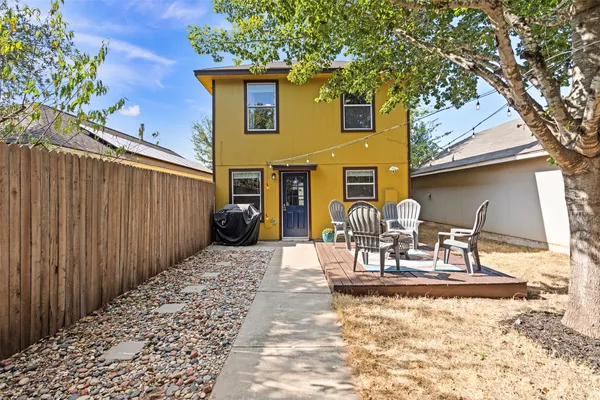a view of a patio with table and chairs with wooden fence and large trees