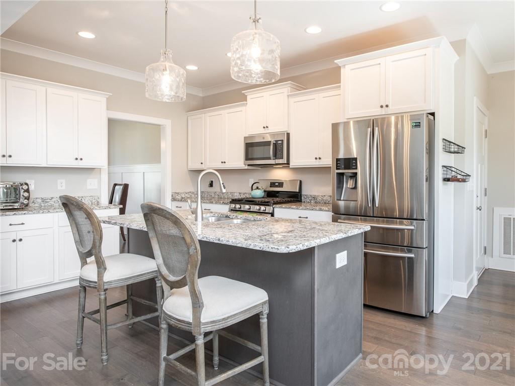 763 Red Spruce Road York, SC 29745 - Photo 40 of 43 a kitchen with stainless steel appliances granite countertop a stove refrigerator a sink dishwasher a dining table and chairs with wooden floor
