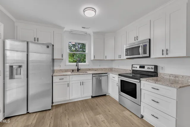 a kitchen with stainless steel appliances granite countertop a sink a stove a dining table and chairs