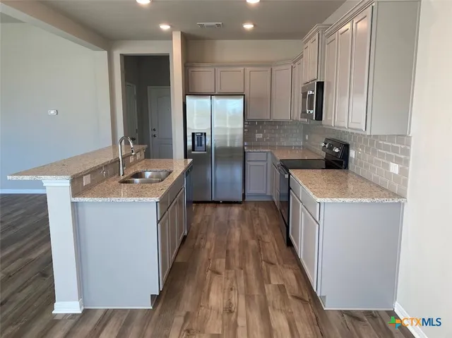 a kitchen with a sink stove top oven and refrigerator