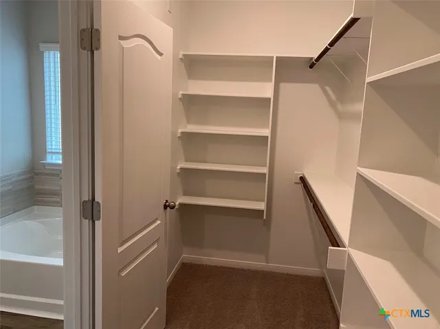 a view of walk in closet with empty racks