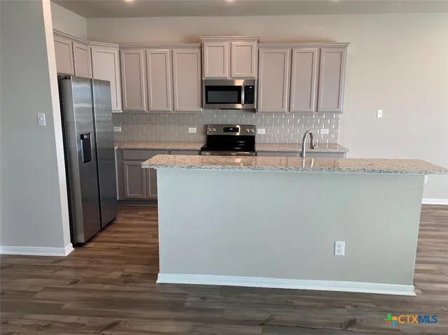 a kitchen with stainless steel appliances granite countertop a refrigerator a stove a sink and a granite counter tops