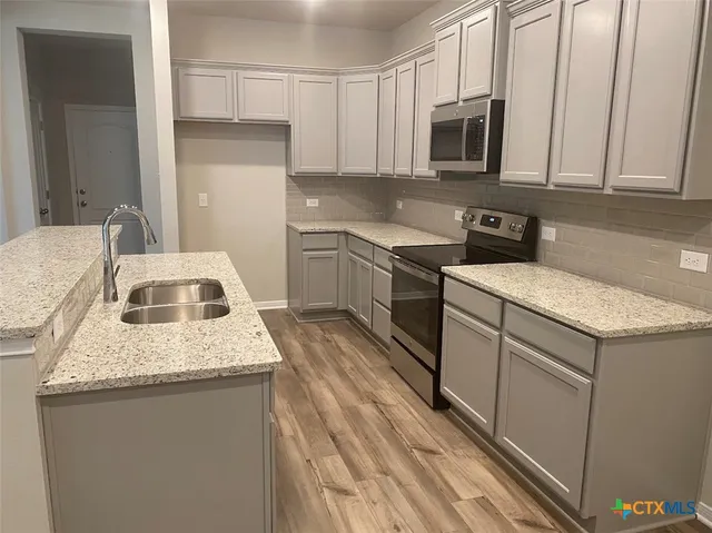 a kitchen with granite countertop a sink a stove and cabinets