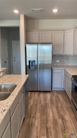 a kitchen with kitchen island granite countertop a sink and a refrigerator