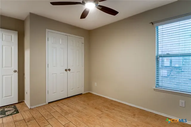an empty room with wooden floor cabinet and windows