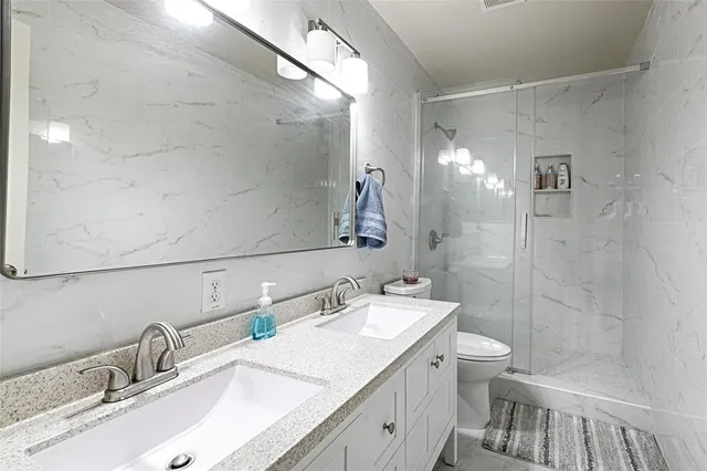 a bathroom with a granite countertop sink a toilet and shower