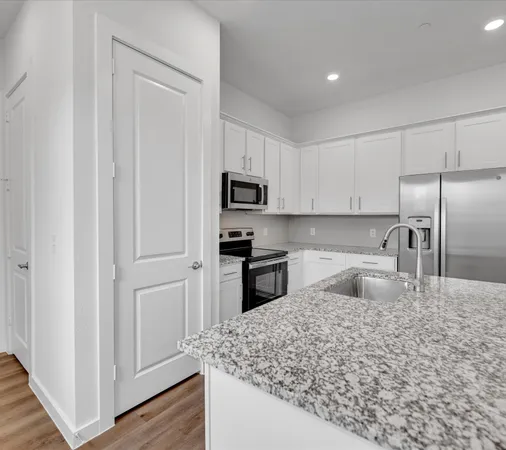a kitchen with granite countertop a refrigerator sink and microwave