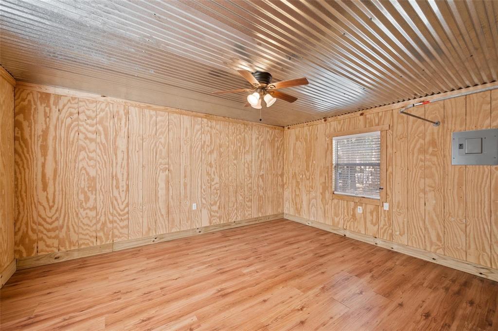134 Maple Avenue Streetman, TX 75859 - Photo 7 of 19 Spare room with light wood finished floors, electric panel, wood walls, and a ceiling fan