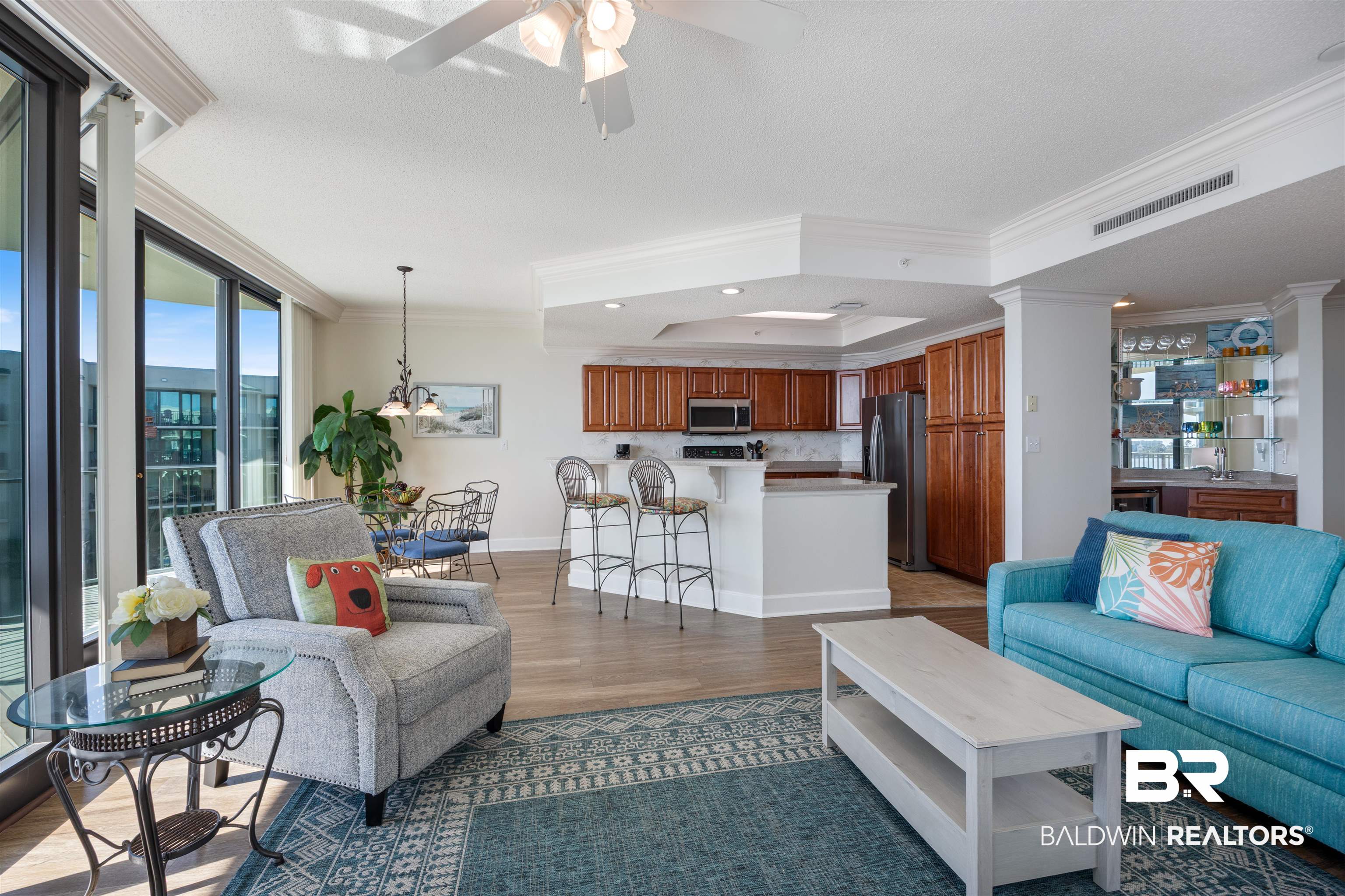 27580 Canal Road, Unit 1431 Orange Beach, AL 36561 - Photo 12 of 73 Living room featuring a raised ceiling, dark wood-style flooring, ornamental molding, a ceiling fan, and a textured ceiling