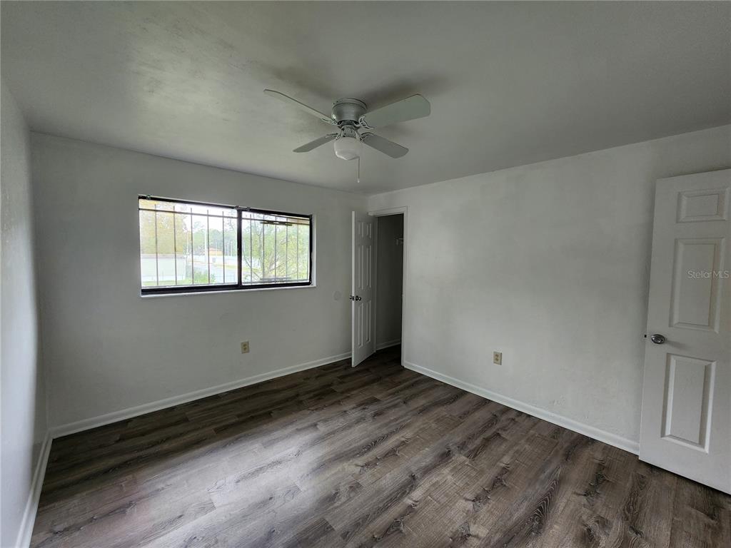 806 Southwest 64th Terrace, Unit C Gainesville, FL 32607 - Photo 22 of 28 an empty room with wooden floor ceiling fan and windows