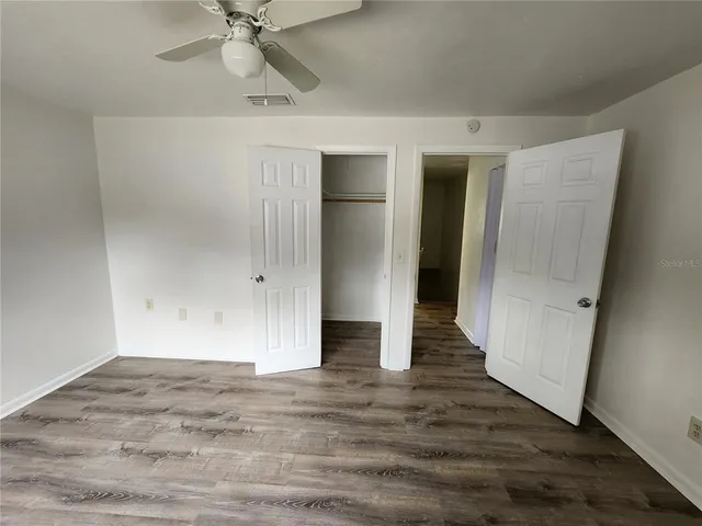 an empty room with wooden floor and fan