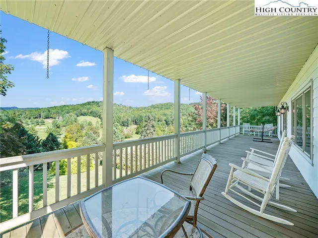 a view of a patio with table and chairs with wooden floor and fence