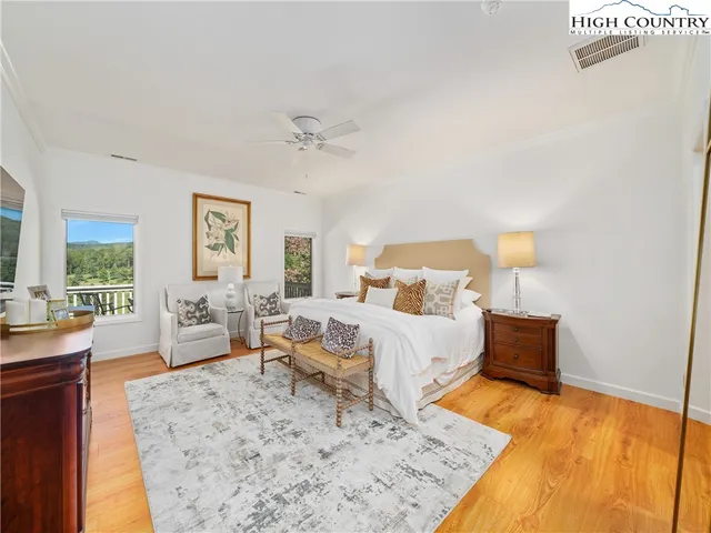 a bed room with a bed couches chair and a large window