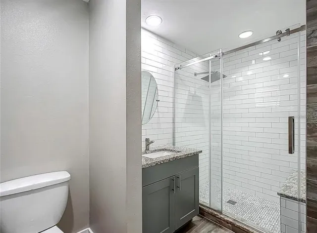a bathroom with a granite countertop sink toilet and shower